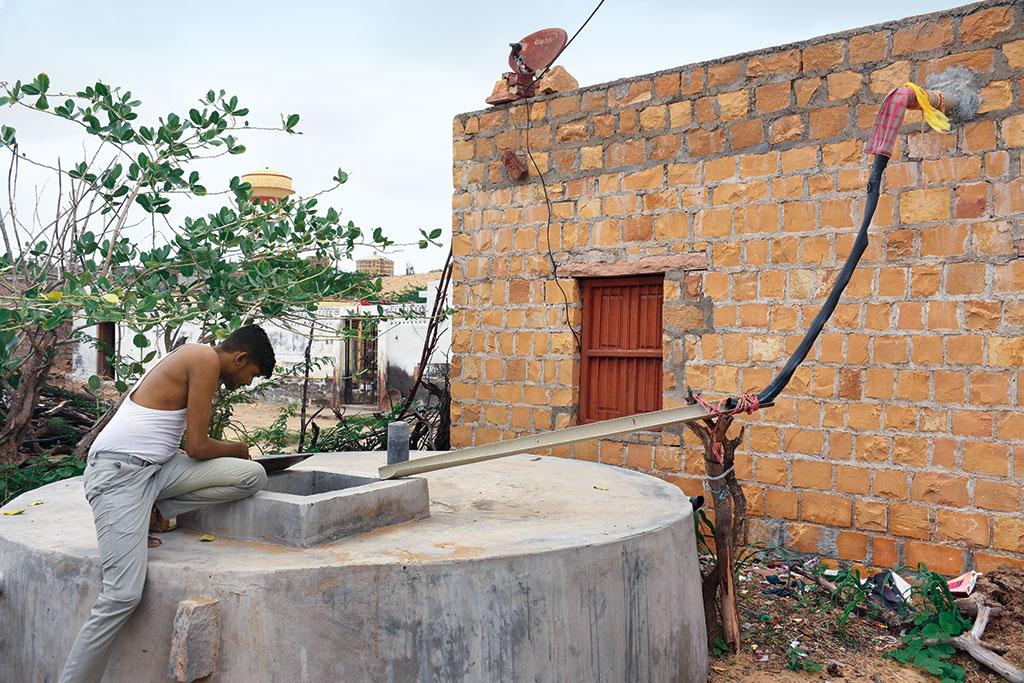 गांव के एक घरेलू टांके पर बने वर्षा जल संचयन के लिए लगाए गए पाइप की जांच करता एक ग्रामीण (फोटो: कपिल वनल)