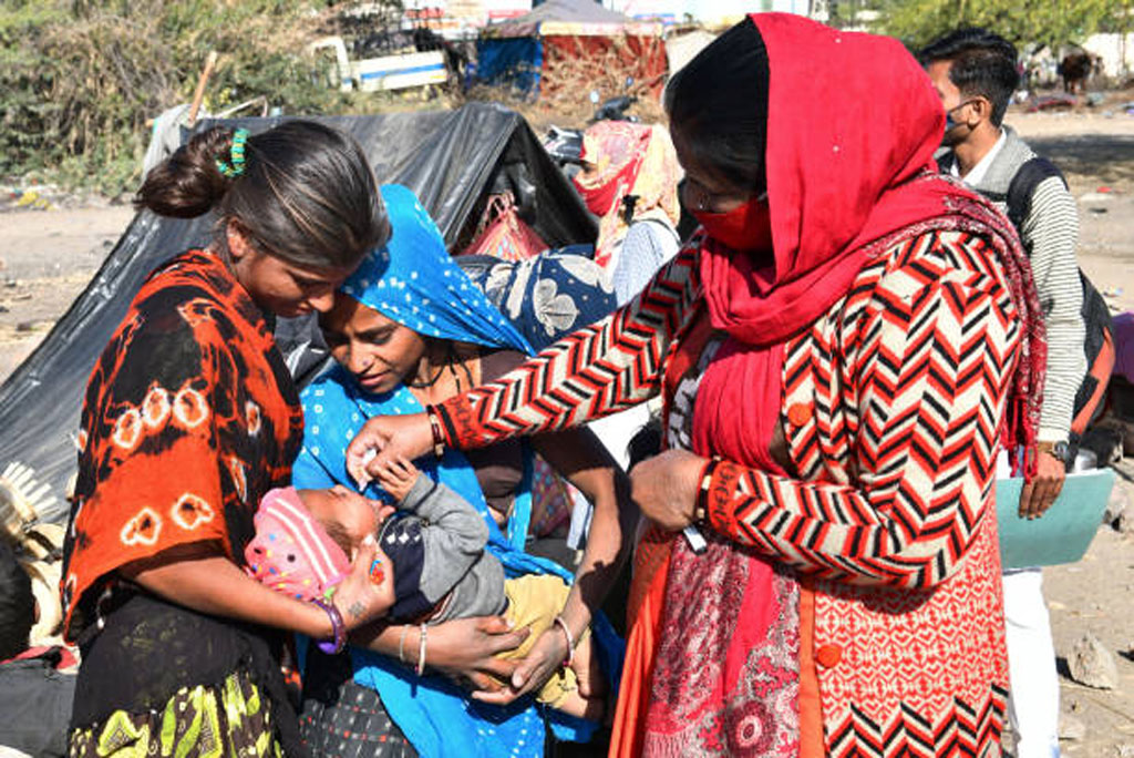 एक फरवरी, 2021:  राजस्थान के ब्यावर में पल्स पोलियो उन्मूलन कार्यक्रम के दौरान एक आंगनवाड़ी स्वास्थ्य कार्यकर्ता एक झुग्गी बस्ती में बच्चे को पोलियो की दवा पिलाती हुई