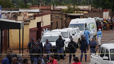 South African police gather at the scene of a mass shooting where gunmen killed nine and injured at least 10 in a pub in Bekkersdal, South Africa, Sunday, Dec. 21, 2025.