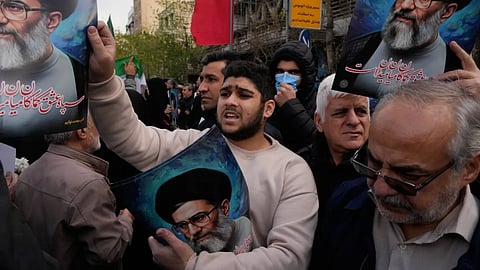 A man hands out posters of the Iranian Supreme Leader Ayatollah Ali Khamenei during a funeral ceremony for a group of security forces, who were killed during anti-government protests