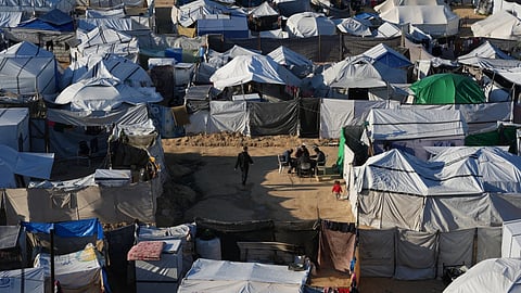 Displaced Palestinians gather outside a tent at a temporary camp in Deir al-Balah, central Gaza Strip