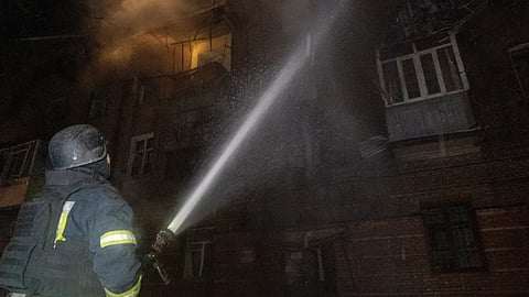 Emergency services personnel work to extinguish a fire following a Russian attack in Kharkiv, Ukraine