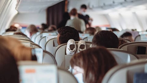 Passengers settle in for their flight as cabin crew attend to in-flight service in the background. (Representative image)