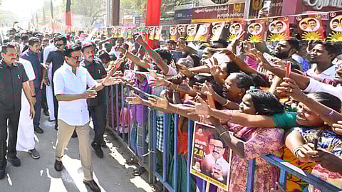 CM Stalin greets enthusiastic supporters as crowds reach out from behind barricades during a public event.