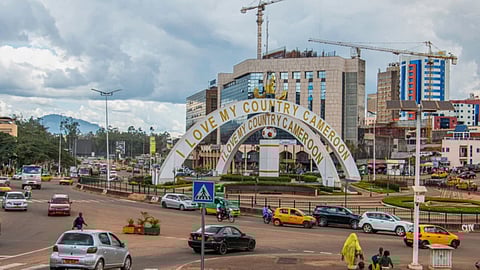 Cars drive through an intersection near a monument in Yaoundé, Cameroon