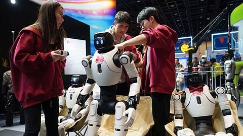 Workers prepare humanoid robots for a performance at a trade fair in Beijing