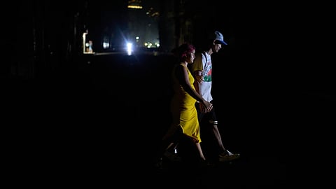 People cross a street during a blackout in Havana