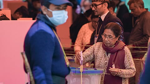 An elderly woman casts a vote in the Nepal general elections, at a polling station in Kathmandu
