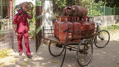 A delivery person carries a used LPG cylinders from a residence.
