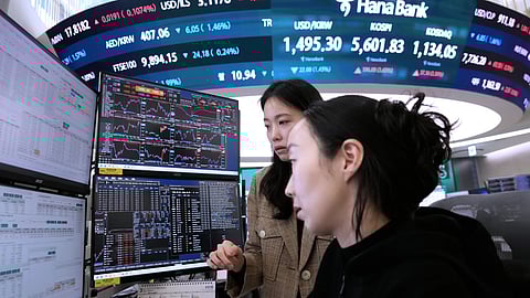 Currency traders watch monitors near a screen showing the Korea Composite Stock Price Index (KOSPI), top center, and the foreign exchange rate between U.S. dollar and South Korean won, top center left, at the foreign exchange dealing room of the Hana Bank headquarters in Seoul, South Korea, Tuesday, March 24, 2026.