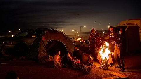 Members of a family, who fled Israeli strikes in southern Lebanon, sit around a bonfire outside a tent used as a shelter in Beirut, Lebanon, Wednesday, March 25, 2026. 