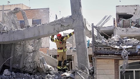 A first responder inspects the damaged structure of a residential building hit in an earlier US-Israeli strike in Tehran