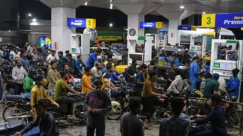 Motorcyclists crowd into a filling station as they wait their turn to buy fuel, in Karachi, Pakistan
