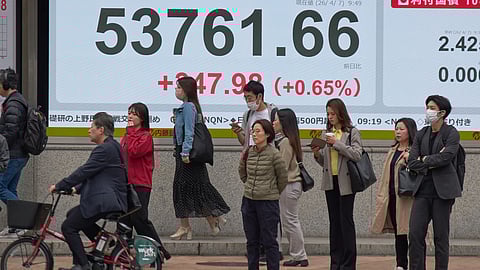 People stand in front of an electronic stock board showing Japan's Nikkei index at a securities firm Tuesday, April 7, 2026, in Tokyo.