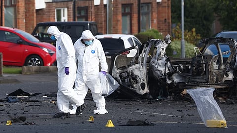 Forensic investigators inspect the site of a car bomb that exploded outside Dunmurry police station in South Belfast, April 26.