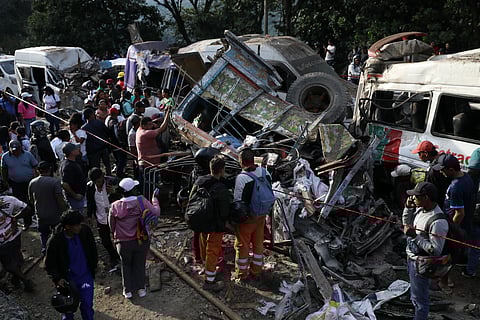   People gather around vehicles damaged in an attack on the Pan-American Highway in Cajibio, Colombia, Saturday, April 25, 2026, that killed at least a dozen people and authorities blamed on dissident groups of the former FARC rebels.