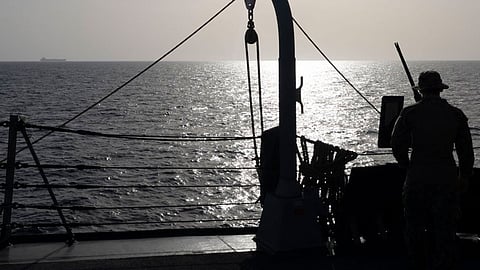 A US Sailor watches a commercial vessel as American forces continue to enforce a blockade against Iranian ports