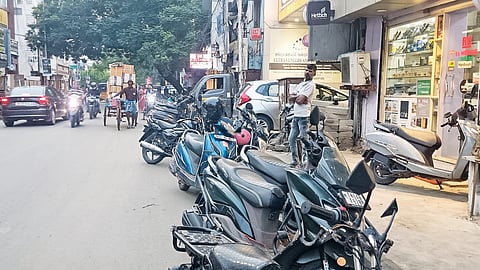 Two-wheelers and autorickshaws are parked on both sides of the road and pavements in Choolai