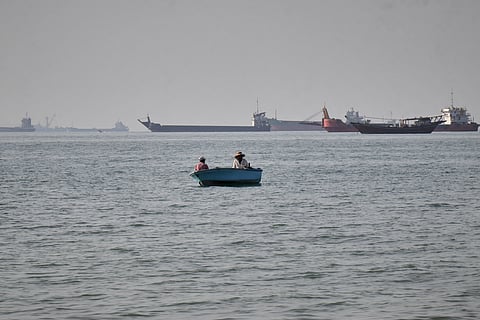 Two men sit in a small boat on the water as a mix of bulk carriers, cargo ships, and service vessels line the horizon in the Strait of Hormuz off Bandar Abbas, Iran, Monday, April 27, 2026.(Razieh
Poudat/ISNA via AP)