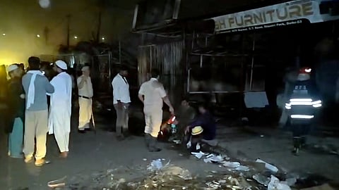 Police personnel and people gather after a fire broke out at a furniture market, in Shastri Park, New Delhi