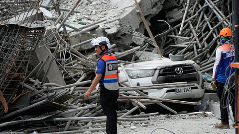 Rescuers stand beside ruins as search operations continue at a collapsed building in Angeles city in Pampanga province, north of Manila, Monday, May 25, 2026. (AP Photo/Aaron Favila)