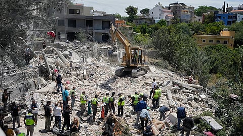 Rescue workers search for victims in the rubble of a destroyed house that was hit on Tuesday by an Israeli airstrike, in the village of Deir Qanoun al Nahr, south Lebanon, Wednesday, May 20, 2026
