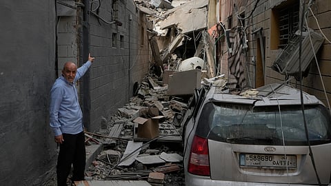  A man points into a destroyed building that was hit in an Israeli airstrike in Burj al-Shemali village