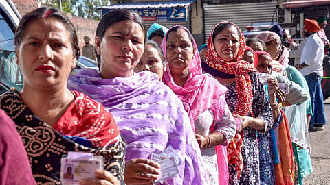 People show their identity cards as they wait in a queue at a polling station to cast their votes during the Municipal Corporation elections, in Amritsar, Punjab