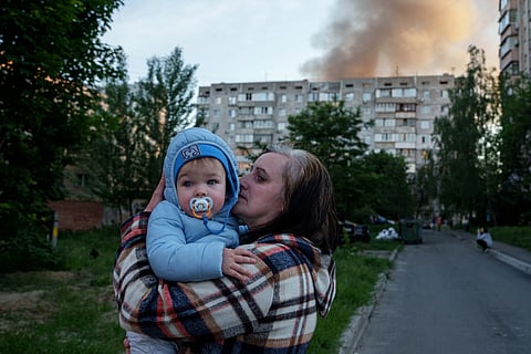 A woman carries a baby near a residential house damaged after a Russian strike in Kyiv, Ukraine, on Tuesday, June 2, 2026