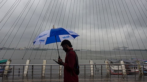 A man covers himself during rainfall as monsoon arrives, at Marine Drive, in Kochi, Kerala, Friday, June 5, 2026