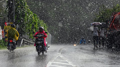 Commuters move along a street during rainfall, in Thiruvananthapuram, Kerala