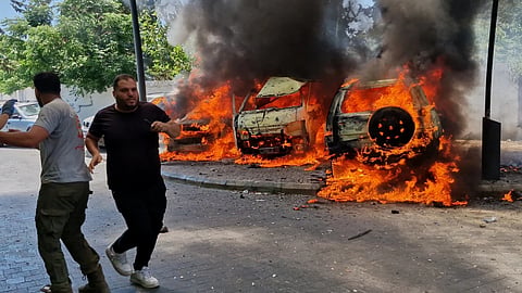  A man runs past burning cars following an Israeli airstrike