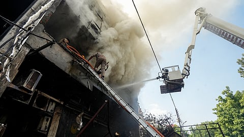 Fire personnel conduct a dousing operation after fire broke out at a commercial building in Aliganj, Lucknow