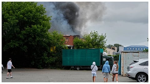 People look at a burning private enterprise following Russian drone attack in Kyiv, Ukraine, Wednesday, July 8, 2026.