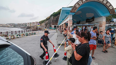 In this photo released by Xinhua News Agency, a security person cordons off the coastal area ahead of Typhoon Bavi's expected arrival in Shitang Town of Wenling City, eastern China's Zhejiang Province, Friday, July 10, 2026.