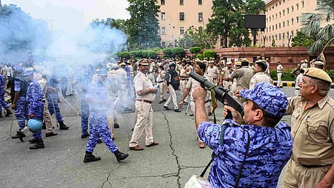 A security officer fires tear gas shells to disperse protesters during a demonstration demanding the resignation of Union Education Minister Dharmendra Pradhan over alleged irregularities in the NEET examination and expressing support for climate activist Sonam Wangchuk, near Shastri Bhawan Metro Station, in New Delhi, Monday, July 20, 2026