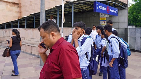 School students wait outside Mandi House Metro station after being stranded for over an hour following the closure of multiple Delhi Metro stations