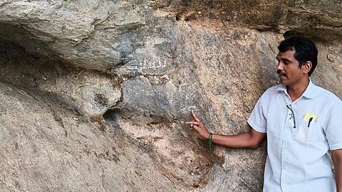 Professor Muneeswaran is seen showing white rock painting which depited reptile like figure, long necked human at Mottamalai near Peraiyur in Madurai district.