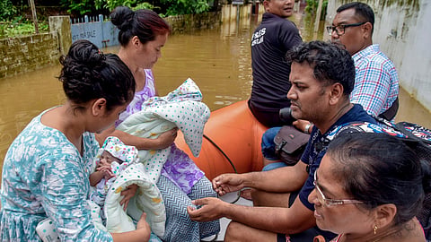 Archer Jayanta Talukdar, centre right, with his family members and one month old twins being moved to a safer place on a rescue boat by SDRF personnel from a flood-affected area at Rukminigaon, in Guwahati