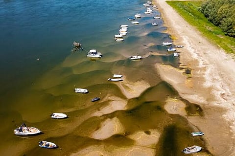  People stand on a bank of sand on the Danube River as usually submerged areas are exposed due to extreme low levels of the water following an extended period of drought in Corabia, Romania, Wednesday, July 29, 2026