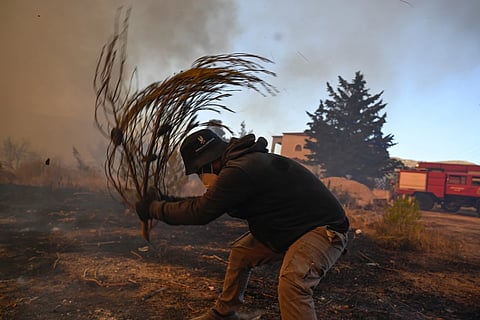  A volunteer tries to extinguish small flames during a wildfire near Porto Germeno, northwest of Athens, Greece, Sunday, Aug. 2, 2026