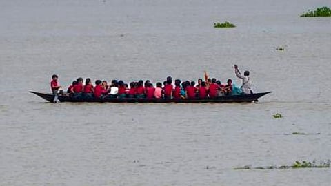 Students travel to school in a country boat after floodwaters submerge roads, in Morigaon district, Assam