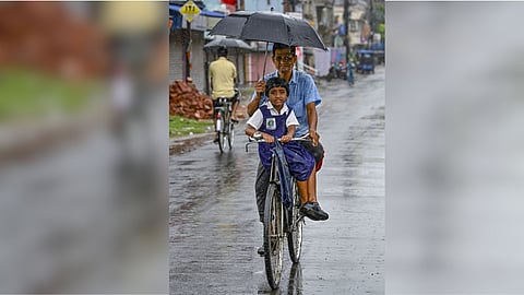 People ride through rain-soaked streets during the monsoon season, in Nadia district, West Bengal.