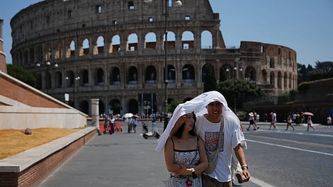 Tourists take shelter as they walk in front of the Rome'a ancient Colosseum