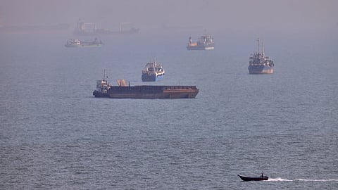  A small boat sails past cargo ships and other commercial vessels anchored in the Strait of Hormuz off Bandar Abbas, Iran