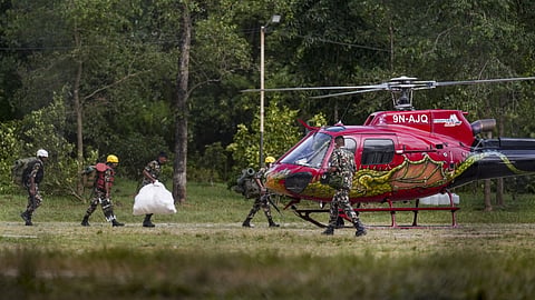 Rescue personnel assist survivors out of a rescue helicopter arriving at the Nepali Army Base Camp at Battar, following their evacuation from a flood-hit area, in Nuwakot district, Nepal.
