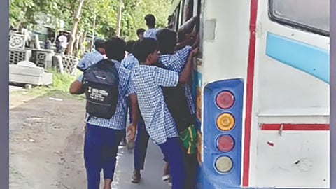 Schoolchildren footboarding on a government bus in Kancheepuram