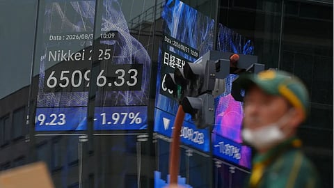 A person walks in front of an electronic stock board showing Japan's Nikkei index at a securities firm, in Tokyo.