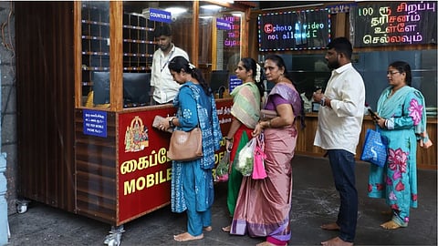 Devotess handling their phone at the counter before entering the temple premises at the Parthasarathy temple in Chennai.