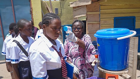 A school official checks students' temperatures as they enter school, on the first day of the new school year amid the Ebola virus outbreak, in Ituri, Congo